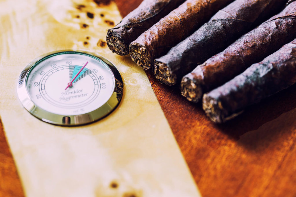 Fresh cigars sit next to a hygrometer.