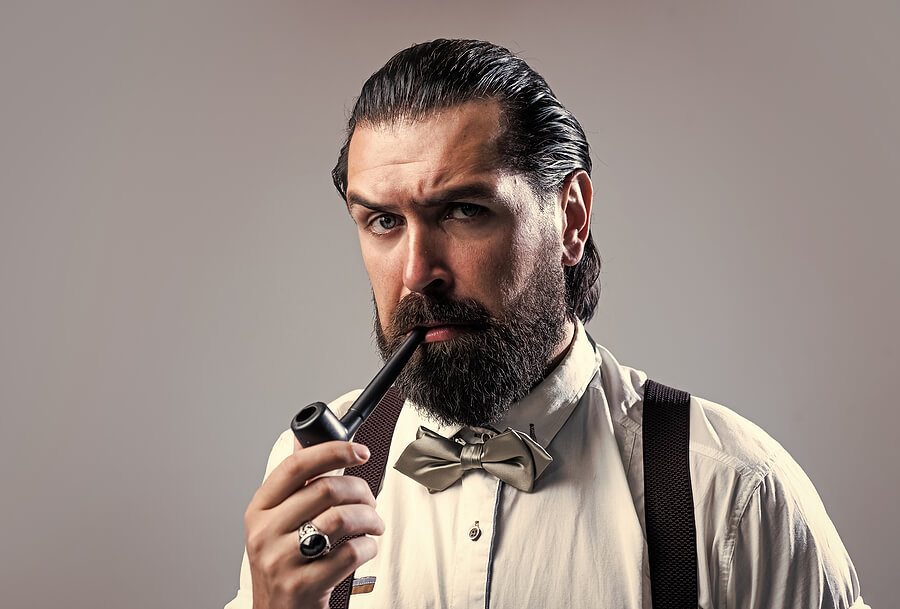 A refined gentleman enjoys a smoke on his freshly packed tobacco pipe